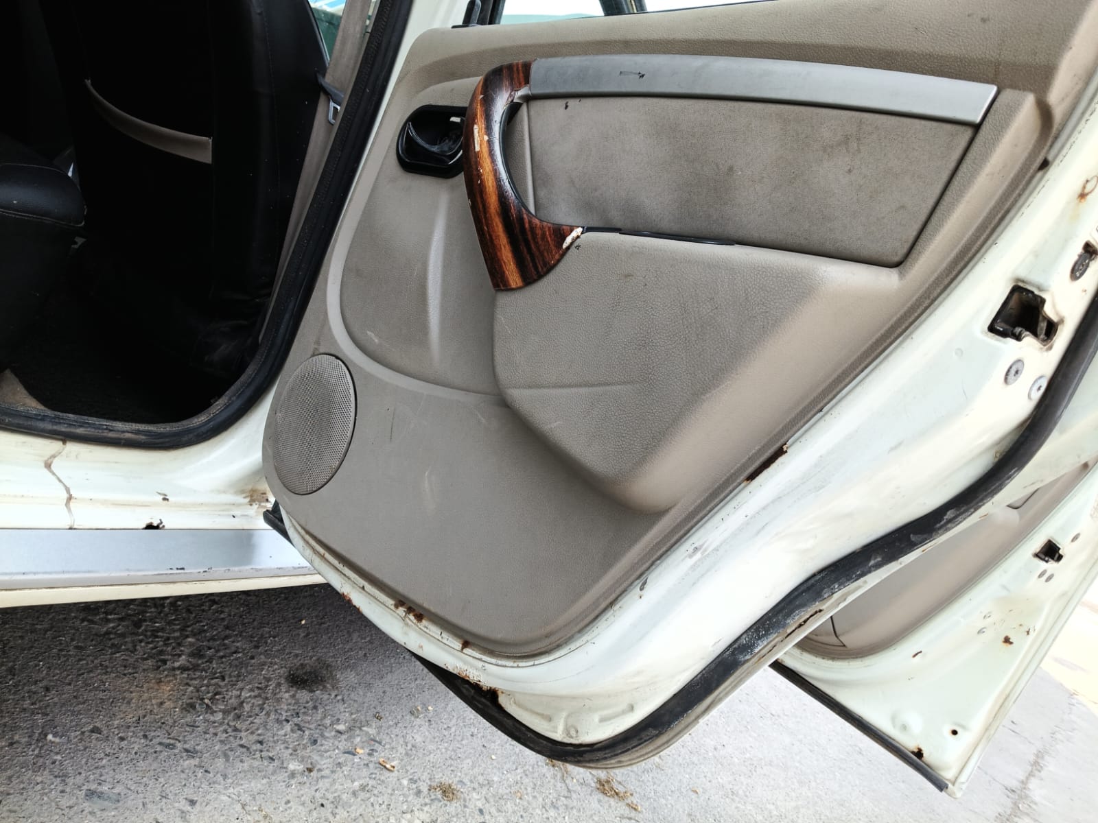 Car door interior panel with speaker, trim, and lower rust marks