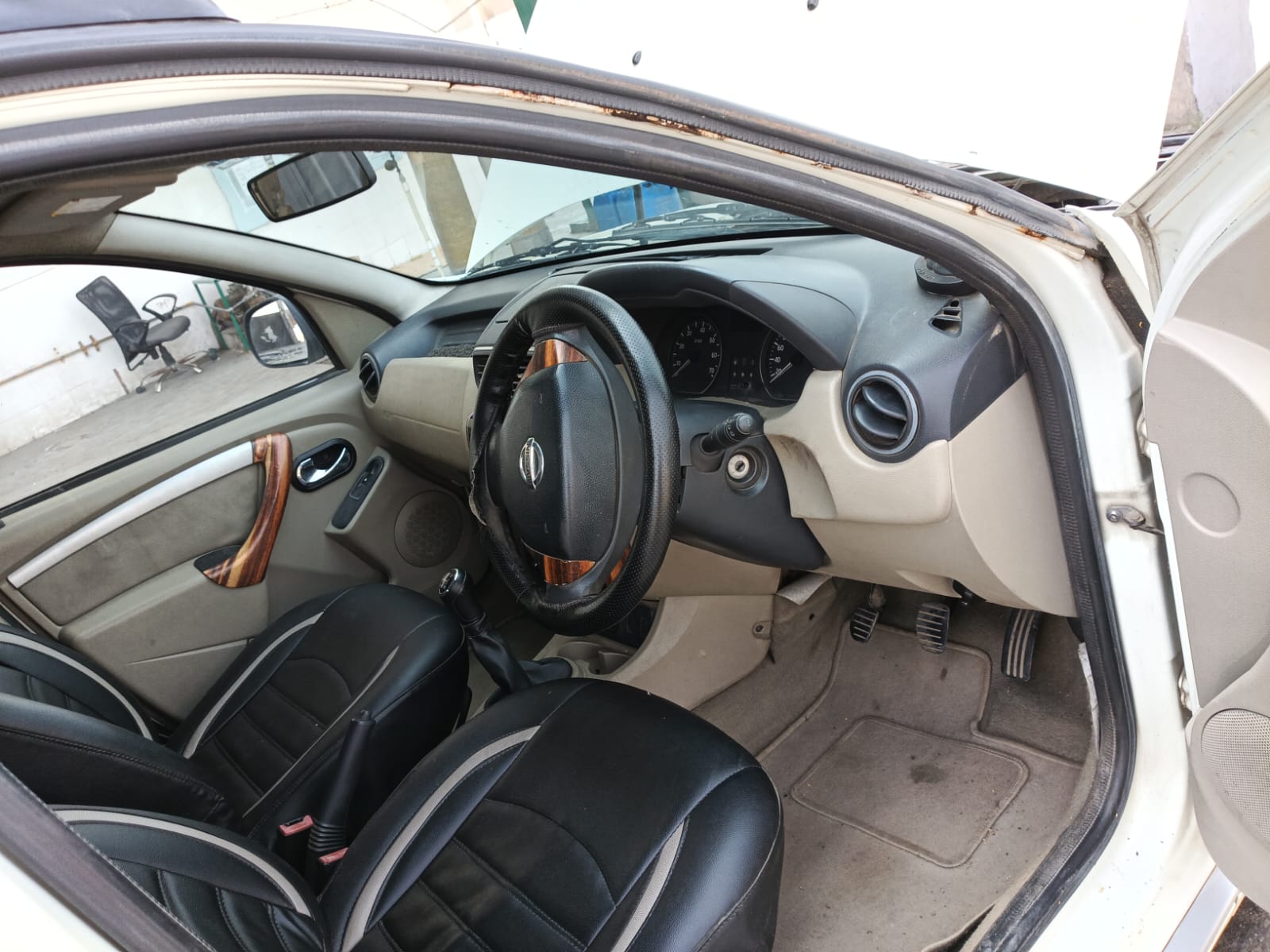 Driver cabin overview showing steering, pedals, seats, and floor mats