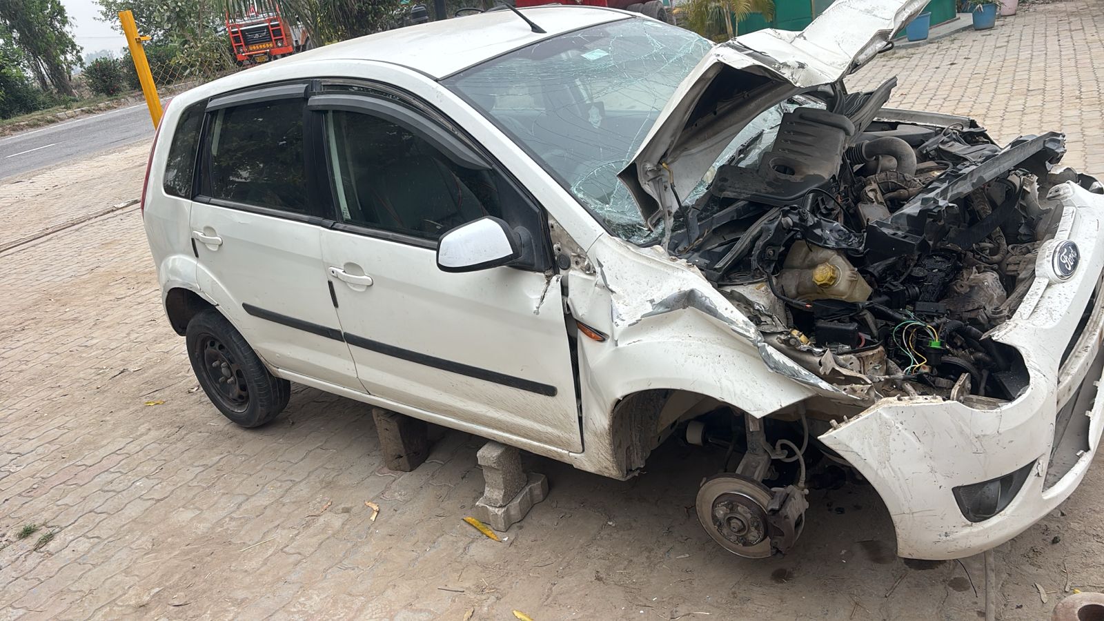 White Ford Figo with heavy front-end accident damage and open bonnet