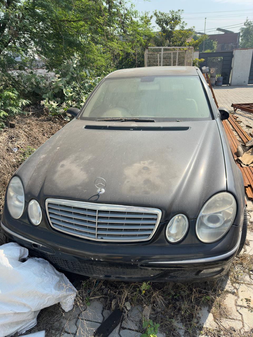 Black Mercedes sedan parked at yard with dusty exterior