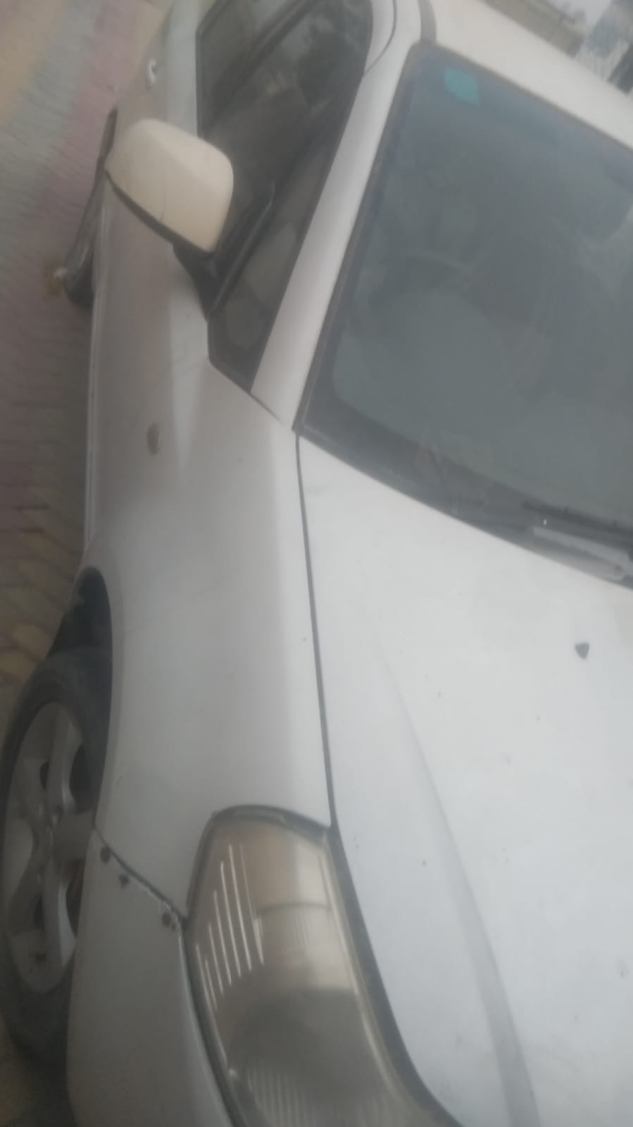 White hatchback front side view captured during vehicle inspection